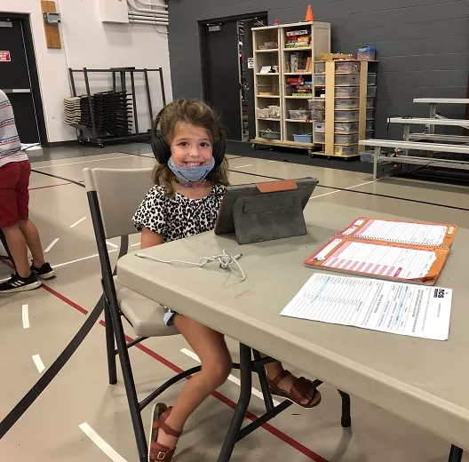 A student is smiling while sitting at a laptop.