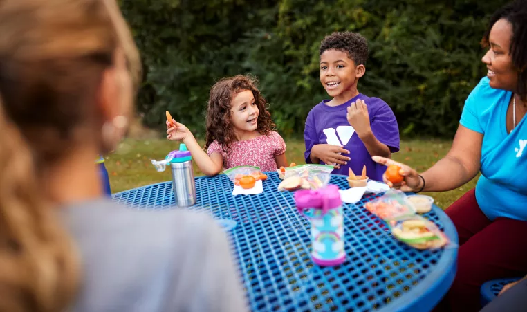 Two children eating at a picnic table.